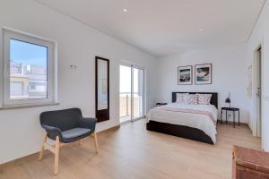 a white bedroom with a bed and a chair at FormosaFuzeta Seaview @Homesbyfc in Fuzeta