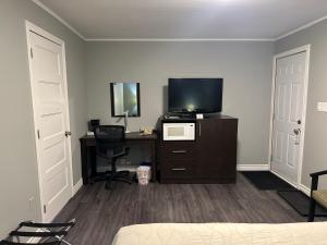 1 dormitorio con TV y escritorio con ordenador en Time Travellers Motel en Petawawa