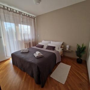 een slaapkamer met een groot bed en handdoeken bij Apartman Via Casa in Vinkovci