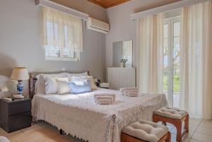 una camera da letto con un grande letto con lenzuola e cuscini bianchi di Heliotropio a Kalamákion