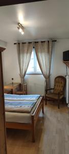 1 dormitorio con 1 cama, 1 silla y 1 ventana en Chambre d'hôtes de la tulipe, en Mittelbergheim