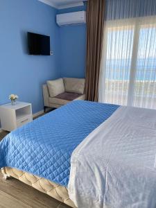 a blue bedroom with a large bed and a chair at Persephone in Himare