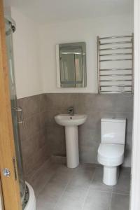 a bathroom with a sink and a toilet and a mirror at The White House in Wirral