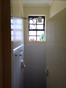 a bathroom with a window and a white tiled shower at Tranquil haven - spacious, cozy, 1 bedroom in Kisumu