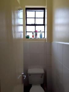 a bathroom with a toilet and a window at Tranquil haven - spacious, cozy, 1 bedroom in Kisumu