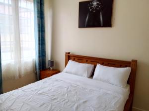 a bedroom with a bed with white sheets at Tranquil haven - spacious, cozy, 1 bedroom in Kisumu