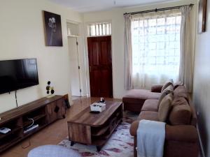 a living room with a couch and a tv at Tranquil haven - spacious, cozy, 1 bedroom in Kisumu