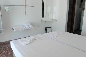 a white room with two beds and towels at Klironomos Apartments Logaras in Logaras