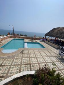 uma piscina com piso em azulejo e um telhado de palha em Casa vista mar em Salina Cruz