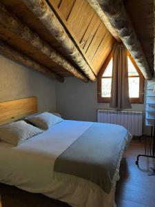 a bedroom with a large white bed with wooden ceilings at Cal Lluch in Víllec
