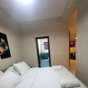 una camera da letto con un letto con lenzuola bianche e uno specchio di @Bazaar a Tirana
