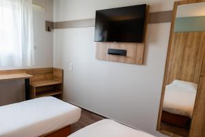 a small room with two beds and a flat screen tv at B&B HOTEL Pau Lescar in Lescar +47 photos