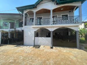 Cette maison blanche dispose de deux portes et d'un balcon. dans l'établissement TrierHouse, à Douala
