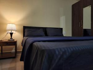 a bedroom with a bed with a blue blanket and a lamp at SD D'Souza Heritage Moira Flats with Reserved Parking in Moira