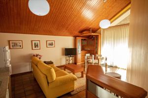 a living room with a yellow couch and a television at 2 bedrooms appartement at Vilanova 100 m away from the beach with sea view enclosed garden and wifi in Aldán