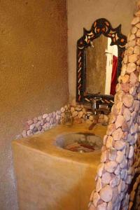 a bathroom with a stone sink and a mirror at Riad Les 5 Lunes in Aït Idaïr