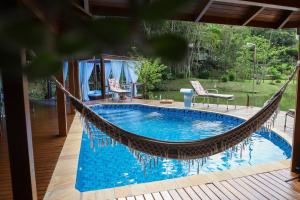 una hamaca sobre una piscina en el patio trasero en Casa de Campo, Refúgio do Lago, en Itajaí