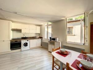 een keuken met witte kasten en een tafel en een eetkamer bij Gorges du Verdon - Hyper centre Castellane - Rue Piétonne - Studio 3 Couchages in Castellane