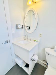 Baño blanco con lavabo y espejo en Seaway Inn en Santa Cruz