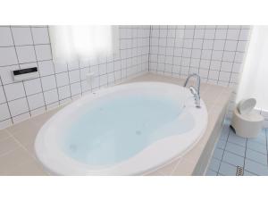 eine weiße Badewanne in einem weiß gefliesten Bad in der Unterkunft TEA TREES - Vacation STAY 86519v in Tateyama