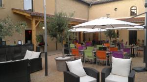 a patio with tables and chairs and an umbrella at Hôtel Restaurant Carpe Diem CLIMATISE in Savigneux