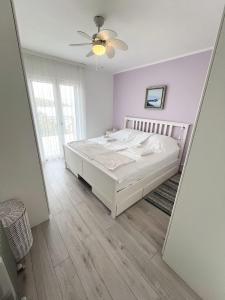 a white bedroom with a bed and a ceiling fan at Leut in Nečujam