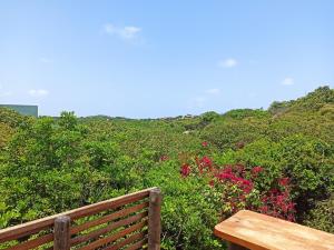 a wooden bench sitting on top of a hill with flowers at Casa Vermelha in Pipa