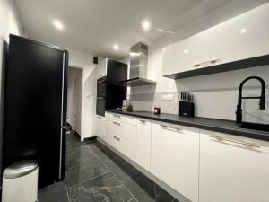 a kitchen with white cabinets and black counter tops at Love Games in Plérin