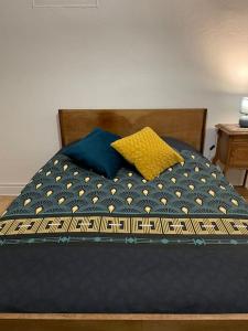 a bed with a blue comforter and a yellow pillow at le gite de Justine et Agathe in Verdun-sur-Meuse