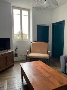 a living room with a couch and a table and a tv at le gite de Justine et Agathe in Verdun-sur-Meuse