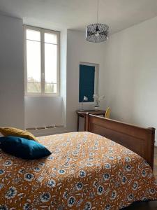 a bedroom with a bed with a blue pillow on it at le gite de Justine et Agathe in Verdun-sur-Meuse