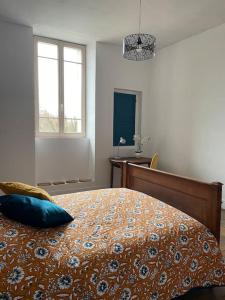 a bedroom with a bed with a blue pillow on it at le gite de Justine et Agathe in Verdun