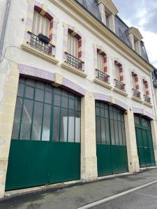 a building with green doors and windows on a street at le gite de Justine et Agathe in Verdun-sur-Meuse