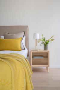 a bed with a yellow blanket and a night stand with a plant at Neighbourgood Old Cape Quarter in Cape Town