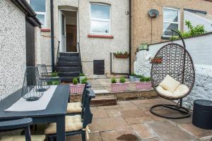 a patio with a table and a chair in front of a house at Lavender Terrace in Llandudno