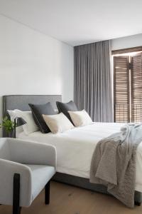 - une chambre avec un grand lit blanc et une chaise dans l'établissement Neighbourgood Old Cape Quarter, au Cap