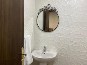 baño con lavabo y espejo en la pared en Hôtel Meuble Parisien, en Rabat