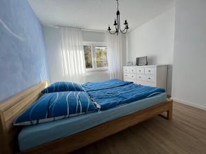 una camera da letto con un letto con lenzuola blu e una finestra di Ferienhaus EifelOne a Heimbach