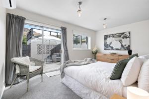 um quarto com uma cama, uma cadeira e uma janela em Lake and Mountain view living em Queenstown