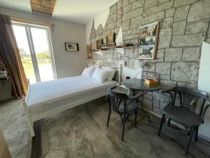 a bedroom with a bed and a table and a stone wall at Efi studios in Kardamaina