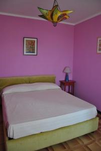 1 dormitorio con 1 cama con pared de color rosa en B&B La vecchia quercia Home Restaurant, en Fornovo di Taro