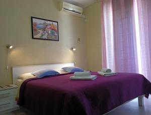 a bedroom with a purple bed with towels on it at Rooms Ivan in Dubrovnik