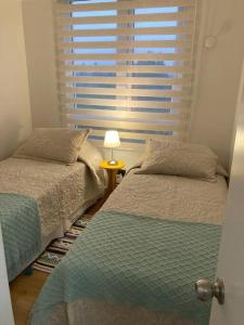 two beds in a room with a window and a lamp at Acogedor depto. Los Angeles in Los Ángeles