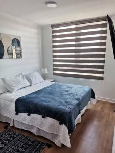 a bedroom with a bed with a blue blanket on it at Acogedor depto. Los Angeles in Los Ángeles