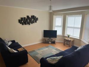 een woonkamer met 2 banken en een flatscreen-tv bij Tivoli villas in New Brighton