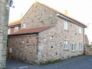 an old stone building with a red roof at Coastal Nest 30 Union Street in Seahouses