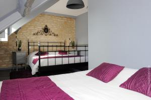 a bedroom with two beds and a brick wall at La Pêcherie in Courseulles-sur-Mer