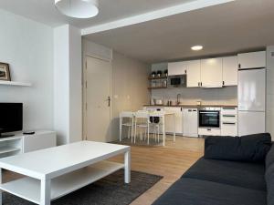 a living room with a white couch and a kitchen at Apartamento Hoznayo in Entrambasaguas