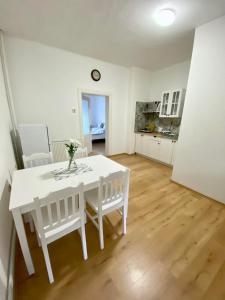 a white dining room table with white chairs and a kitchen at Apartmán Markéta in Bystrzyca