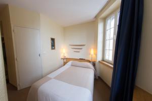 a small bedroom with a white bed and a window at Hôtel San Pedro in Saint Malo